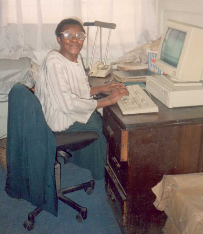 A Kenyan woman sat at her desk using a computer donated from Reusing IT